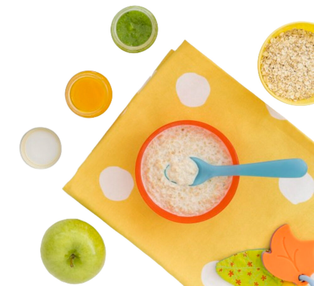 Plato con avena sobre un mantel rodeado de una manzana, otro plato con avena y tres casos con leche y dos jugos diferentes